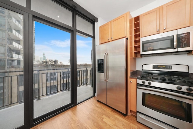 kitchen featuring a view of city, dark countertops, appliances with stainless steel finishes, light wood-style floors, and light brown cabinets