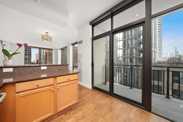 kitchen featuring light wood-style floors, a view of city, a wealth of natural light, and dark stone countertops