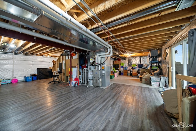 basement with heating unit, hardwood / wood-style floors, and water heater