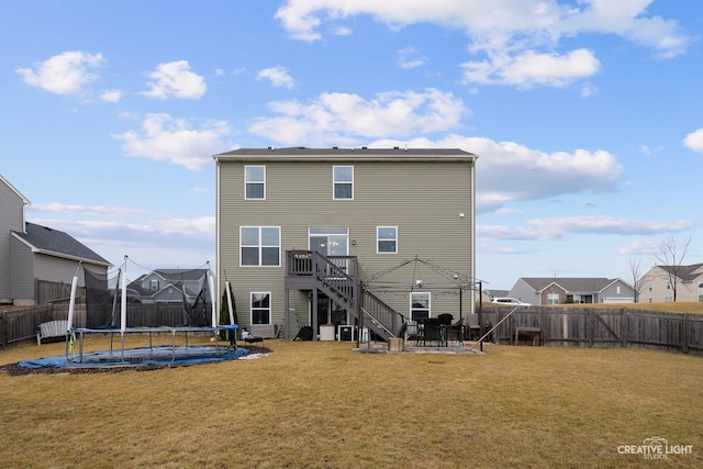 rear view of house with a yard, a patio, and a trampoline