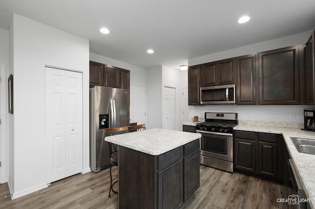 kitchen featuring stainless steel appliances, a kitchen breakfast bar, wood-type flooring, and a kitchen island