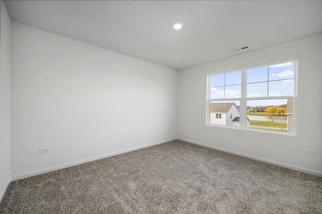 carpeted empty room featuring a water view