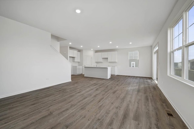 unfurnished living room featuring dark hardwood / wood-style floors and a wealth of natural light