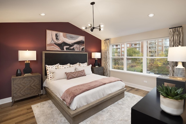 bedroom featuring wood-type flooring, lofted ceiling, and a chandelier