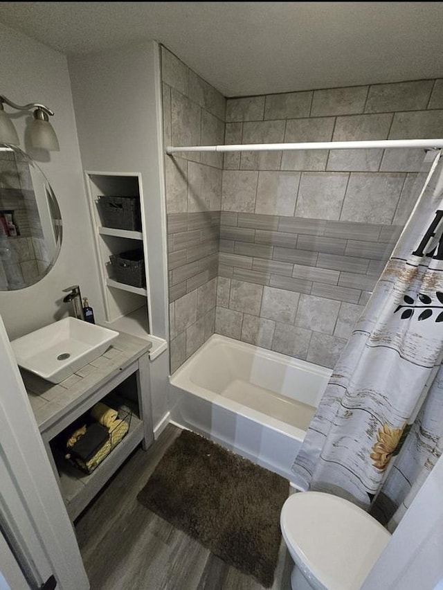 full bathroom featuring toilet, sink, a textured ceiling, shower / bath combo with shower curtain, and hardwood / wood-style floors