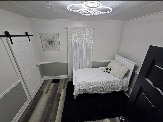 bedroom with a barn door and dark hardwood / wood-style flooring