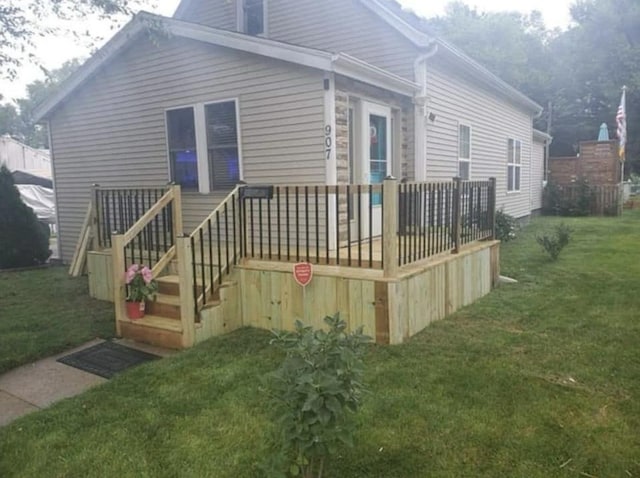 rear view of property with a wooden deck and a yard