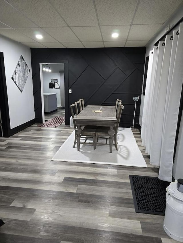 dining area featuring wood-type flooring and a drop ceiling