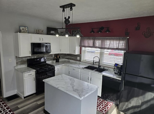 kitchen featuring decorative light fixtures, white cabinetry, sink, a center island, and black appliances