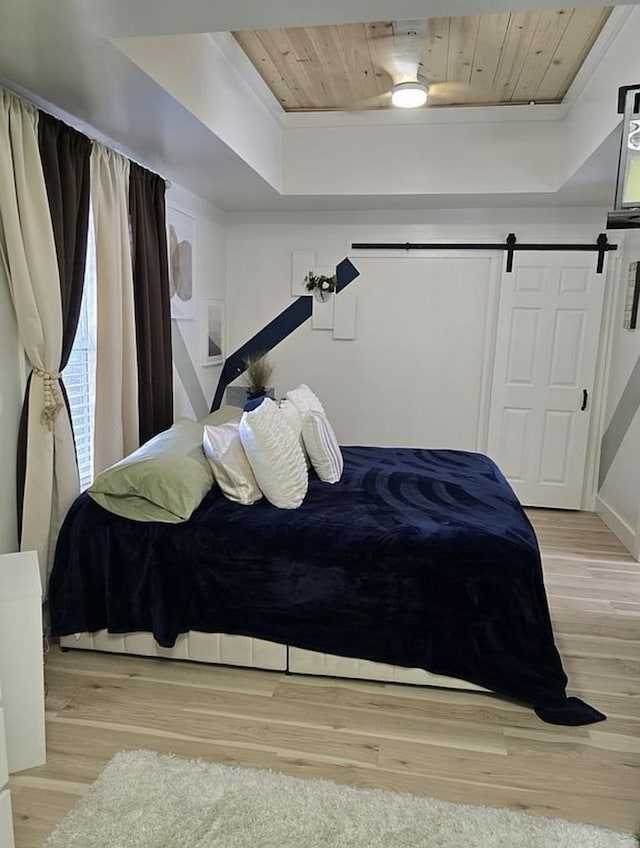 bedroom featuring a barn door, light wood-type flooring, and wood ceiling