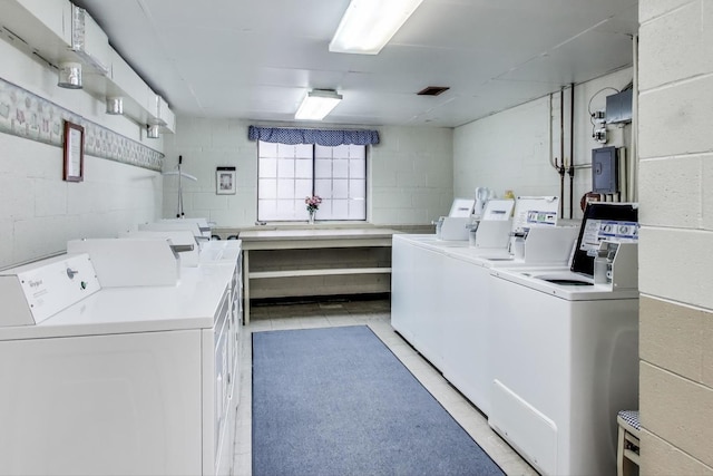 clothes washing area with concrete block wall and separate washer and dryer