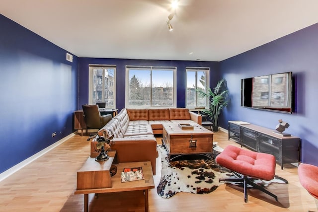 living room with light wood-type flooring, rail lighting, visible vents, and baseboards