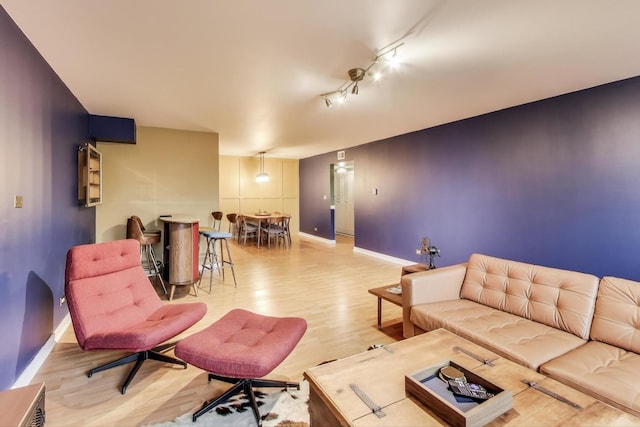 living room featuring light wood-style floors, baseboards, and rail lighting