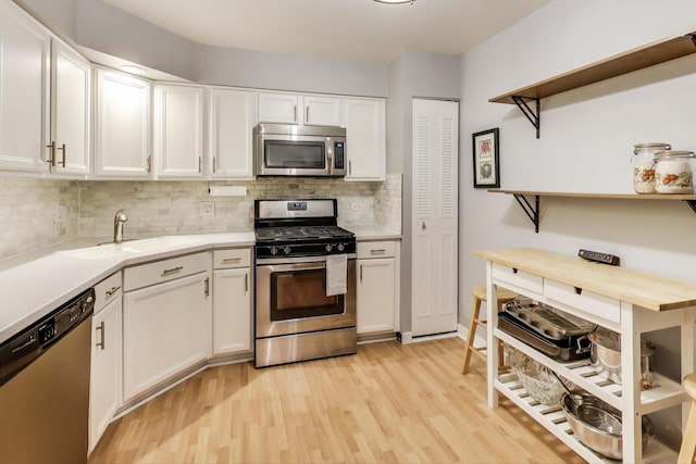 kitchen featuring a sink, white cabinetry, light wood-style floors, light countertops, and appliances with stainless steel finishes