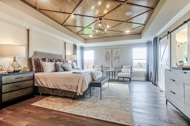 bedroom with dark wood-type flooring, a barn door, and a raised ceiling