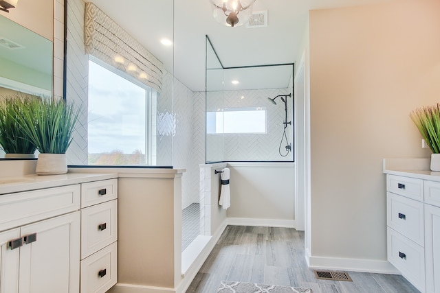 bathroom with a tile shower, vanity, and hardwood / wood-style floors