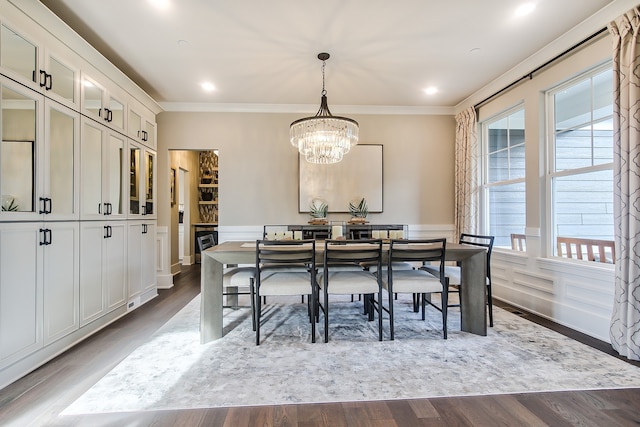 dining space with hardwood / wood-style flooring, ornamental molding, and a chandelier