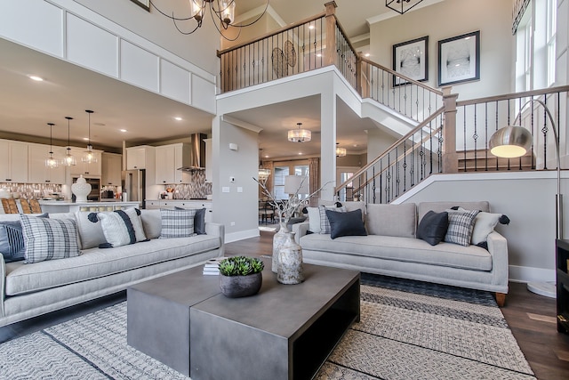 living room featuring crown molding, a towering ceiling, dark hardwood / wood-style floors, and a notable chandelier