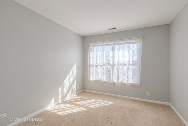 spare room with light colored carpet, visible vents, and baseboards