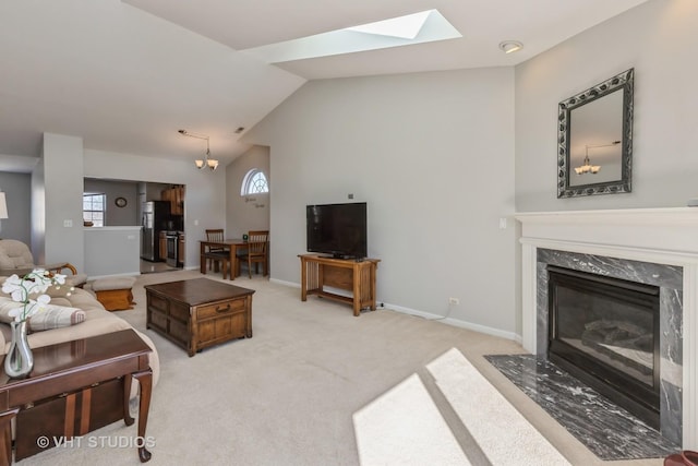 living area with baseboards, light colored carpet, lofted ceiling, a fireplace, and a chandelier