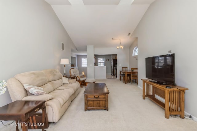 living area featuring high vaulted ceiling, light colored carpet, visible vents, baseboards, and an inviting chandelier