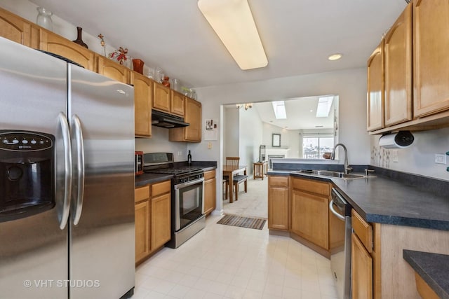 kitchen featuring dark countertops, under cabinet range hood, stainless steel appliances, and a sink