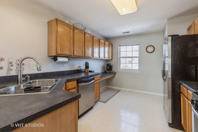 kitchen featuring dark countertops, visible vents, stainless steel appliances, and a sink