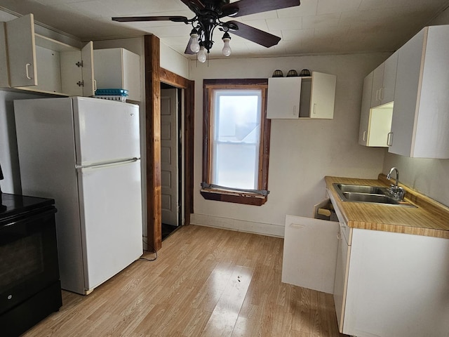 kitchen featuring black / electric stove, white cabinetry, sink, white fridge, and light hardwood / wood-style flooring