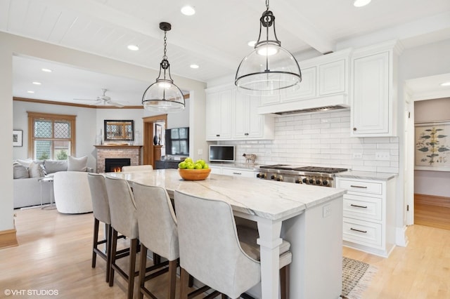 kitchen with beamed ceiling, a kitchen island, range, and white cabinets