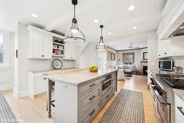 kitchen with stainless steel stove, a breakfast bar, white cabinets, and a kitchen island