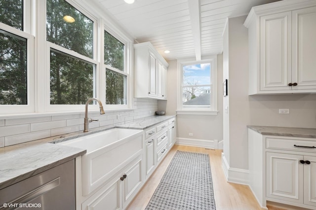 kitchen featuring sink, backsplash, light stone countertops, and white cabinets