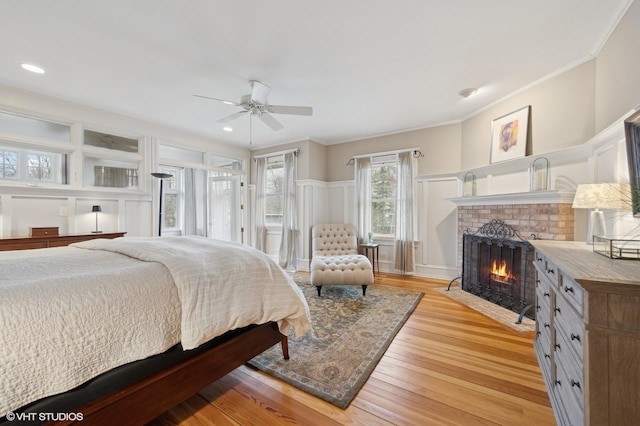 bedroom featuring crown molding, a brick fireplace, ceiling fan, and light wood-type flooring