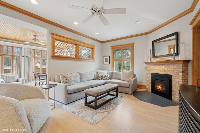 living room featuring ornamental molding, a brick fireplace, ceiling fan, and light wood-type flooring