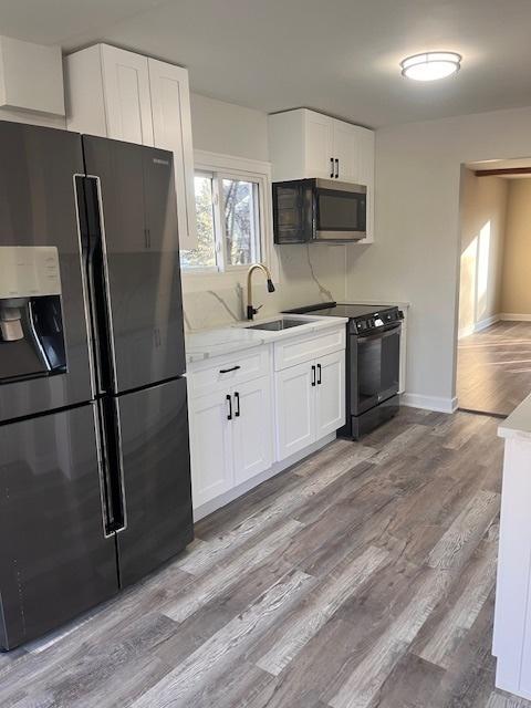 kitchen featuring white cabinetry, light hardwood / wood-style floors, refrigerator with ice dispenser, and electric range