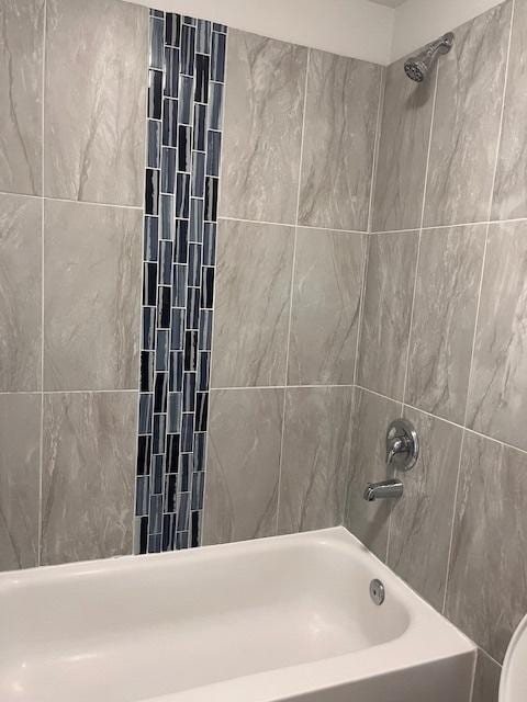 bathroom featuring tiled shower / bath and toilet