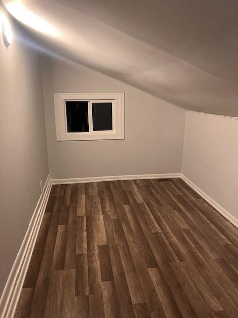 bonus room with dark hardwood / wood-style flooring and vaulted ceiling