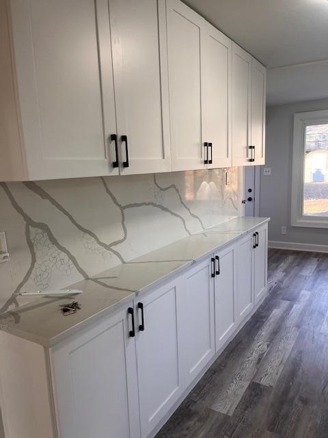 kitchen with white cabinetry, dark hardwood / wood-style floors, light stone counters, and decorative backsplash