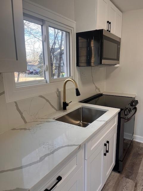 kitchen featuring dark hardwood / wood-style floors, light stone countertops, sink, and white cabinets