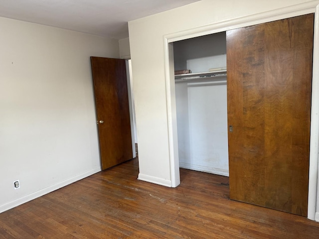 unfurnished bedroom with dark hardwood / wood-style flooring and a closet