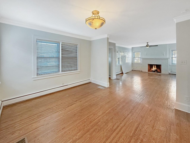 unfurnished living room with ornamental molding, a brick fireplace, a baseboard heating unit, and light hardwood / wood-style flooring