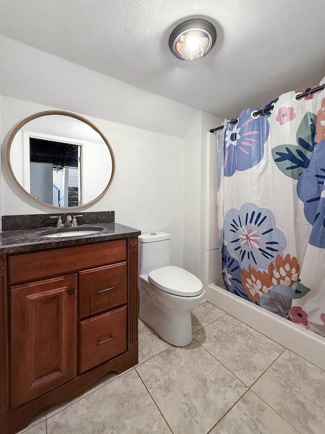 bathroom featuring tile patterned flooring, vanity, a textured ceiling, and toilet