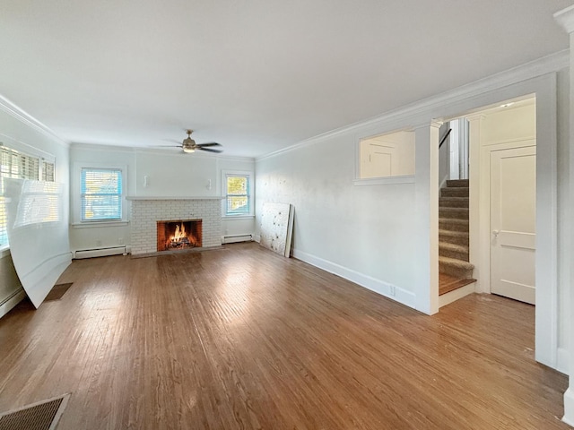 unfurnished living room with hardwood / wood-style floors, ornamental molding, a brick fireplace, and baseboard heating