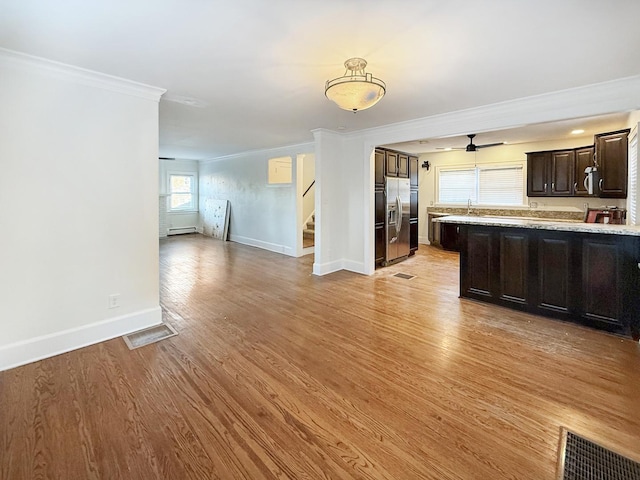 kitchen with stainless steel refrigerator with ice dispenser, ornamental molding, dark brown cabinetry, and light hardwood / wood-style floors