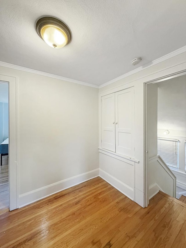 unfurnished bedroom with crown molding, a textured ceiling, and light hardwood / wood-style floors