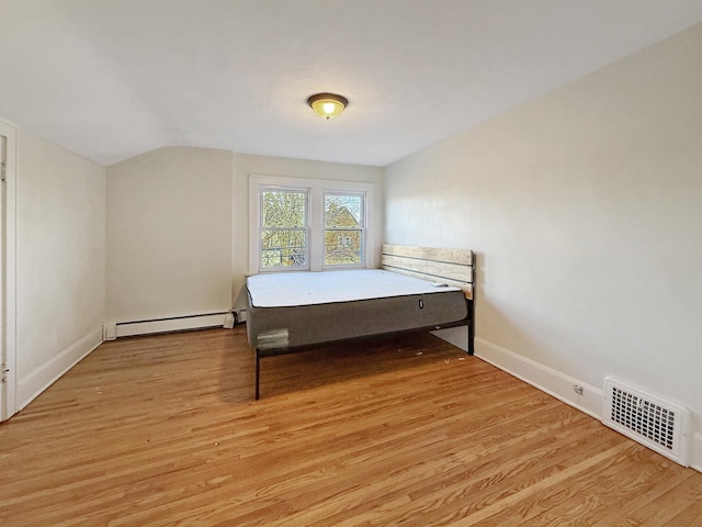 bedroom featuring a baseboard radiator, vaulted ceiling, and light hardwood / wood-style floors