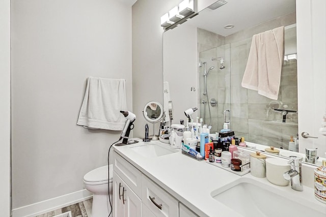 bathroom with baseboards, a sink, a shower stall, and toilet