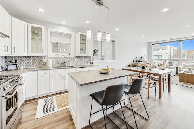 kitchen featuring glass insert cabinets, a center island, white cabinets, and stainless steel gas stove