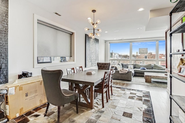 dining room featuring visible vents, an inviting chandelier, expansive windows, a view of city, and recessed lighting