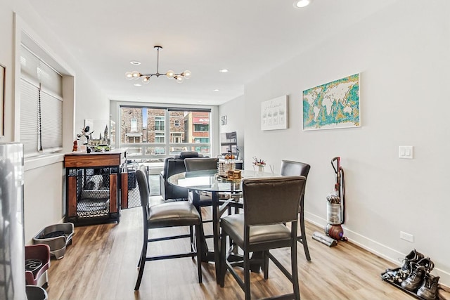 dining area featuring baseboards, light wood finished floors, recessed lighting, and a notable chandelier