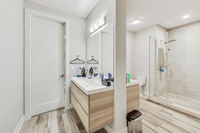 full bathroom with toilet, a stall shower, vanity, wood finished floors, and baseboards